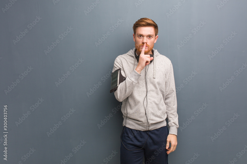 Young fitness redhead man keeping a secret or asking for silence