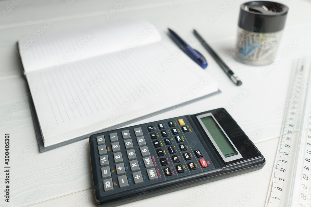 Notebook, calculator, pen, pencil on a white table, side view Notebook, calculator, pen, pencil on a white table, side view