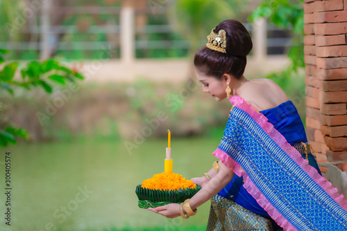 Portrait of beautiful asian woman in Thai dress traditional praying hold kratong for join loy kratong festival at thailand photo