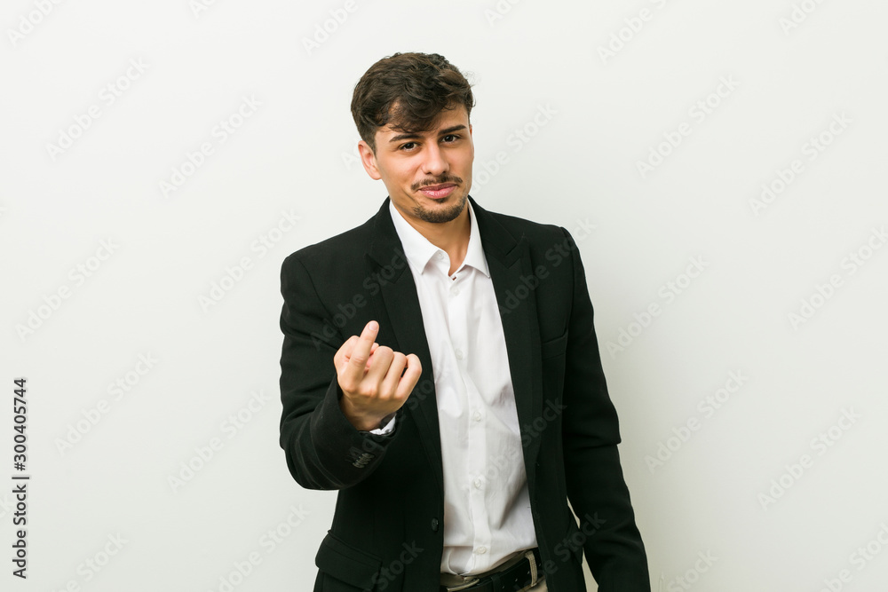 Young business hispanic man pointing with finger at you as if inviting come closer. Young business hispanic man pointing with finger at you as if inviting come closer.