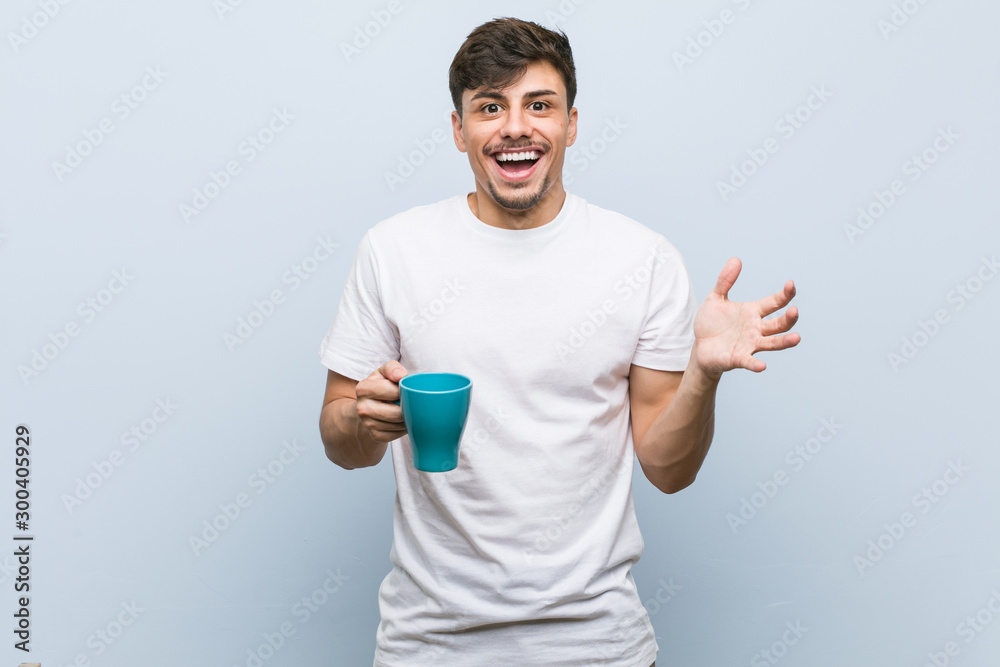 Young hispanic man holding a cup celebrating a victory or success