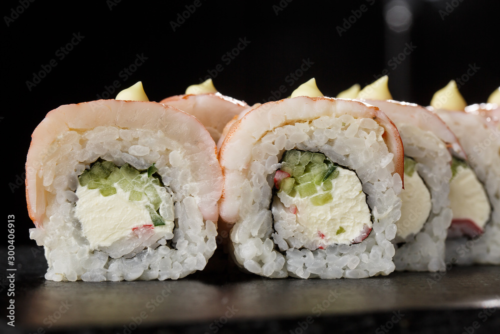 Sushi Rolls with cucumber, shrimp, crab meat and Cream Cheese inside on black slate isolated. Philadelphia roll sushi with shrimp. Sushi menu. Horizontal photo. Sushi Rolls with cucumber, shrimp, crab meat and Cream Cheese inside on black slate isolated. Philadelphia roll sushi with shrimp. Sushi menu. Horizontal photo.