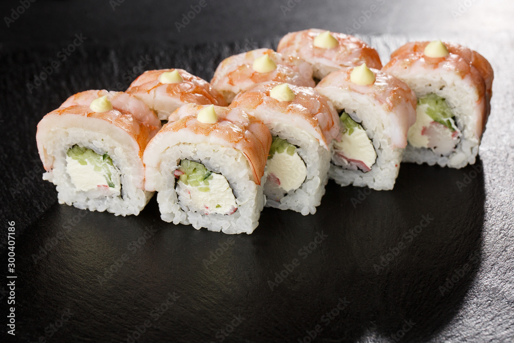 Sushi Rolls with cucumber, shrimp, crab meat and Cream Cheese inside on black slate isolated. Philadelphia roll sushi with shrimp. Sushi menu. Horizontal photo. Sushi Rolls with cucumber, shrimp, crab meat and Cream Cheese inside on black slate isolated. Philadelphia roll sushi with shrimp. Sushi menu. Horizontal photo.