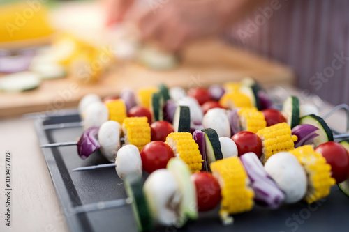 Vegetables on skewers on tray outdoors prepared for grilling on garden barbecue.