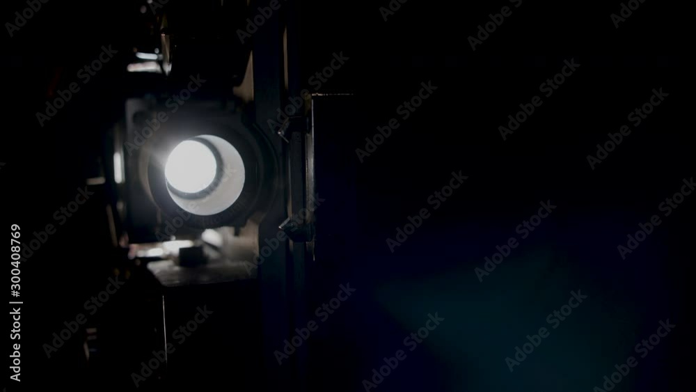 A super eight film projector on a black background, slow motion.
