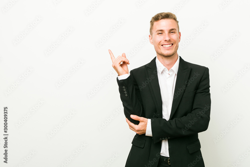 Young caucasian business man smiling cheerfully pointing with forefinger away. Young caucasian business man smiling cheerfully pointing with forefinger away.