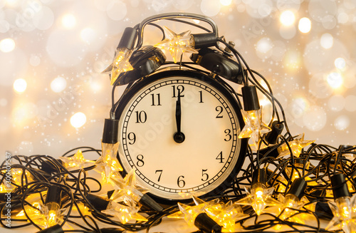 New Year alarm clock wrapped into festive star garland. Midnight.
