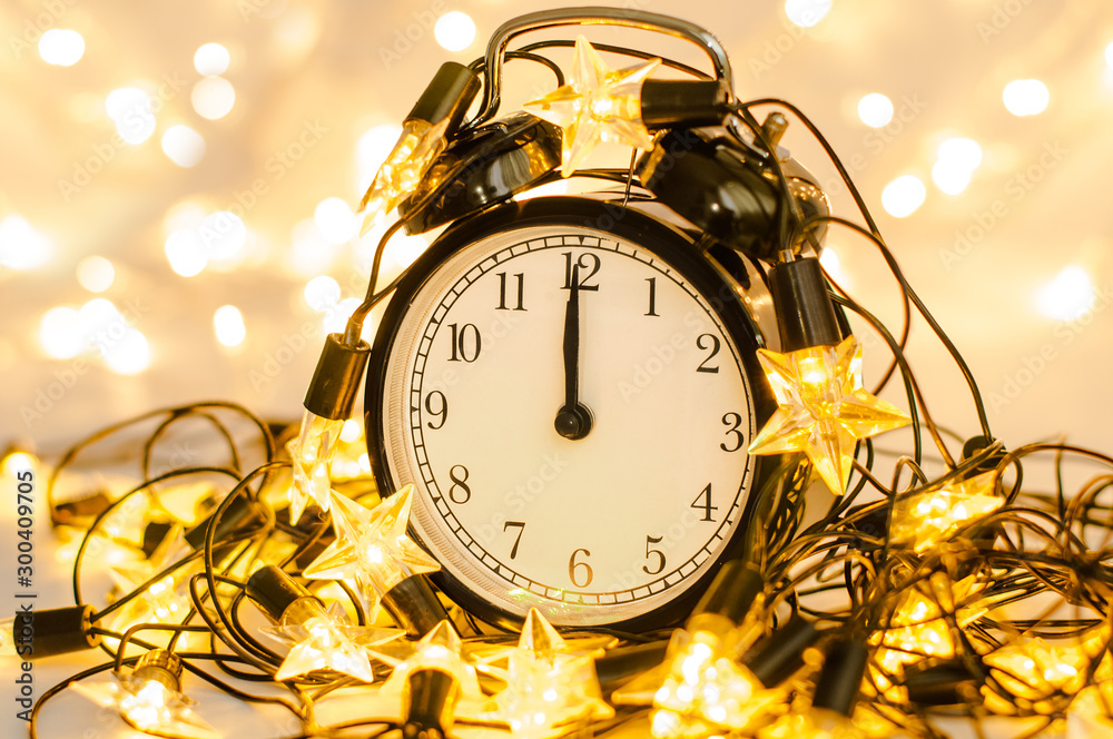 New Year alarm clock wrapped into festive star garland. Midnight. New Year alarm clock wrapped into festive star garland. Midnight.