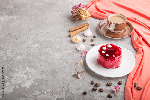 Red cake with souffle cream with cup of coffee on a gray concrete background. side view, copy space.