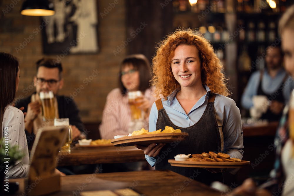 Young happy waitress serving her guest in a pub.