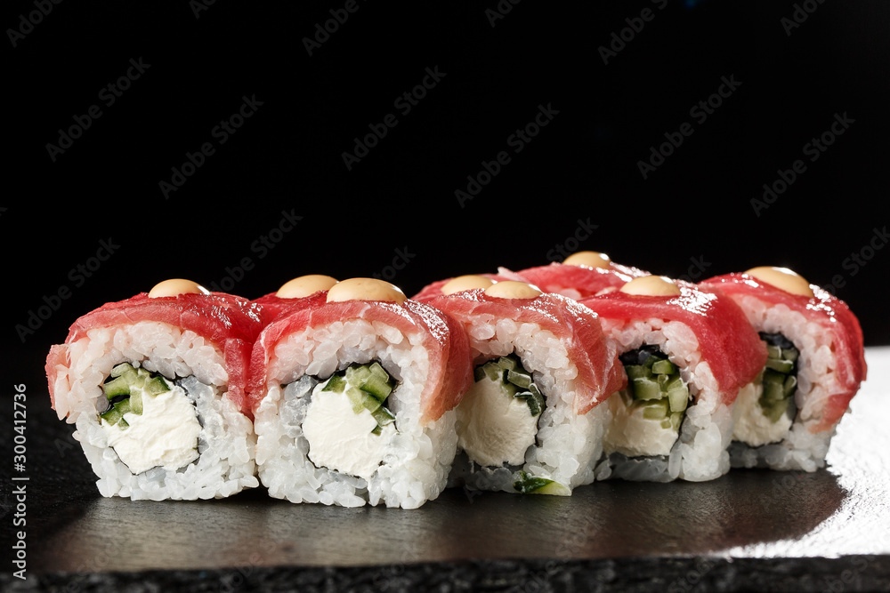 Sushi Rolls with cucumber, tuna, and Cream Cheese inside on black slate isolated. Philadelphia roll sushi with shrimp. Sushi menu. Horizontal photo. Sushi Rolls with cucumber, tuna, and Cream Cheese inside on black slate isolated. Philadelphia roll sushi with shrimp. Sushi menu. Horizontal photo.