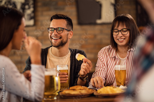 Photography Happy couple drinking beer and eating with friends in a pub.