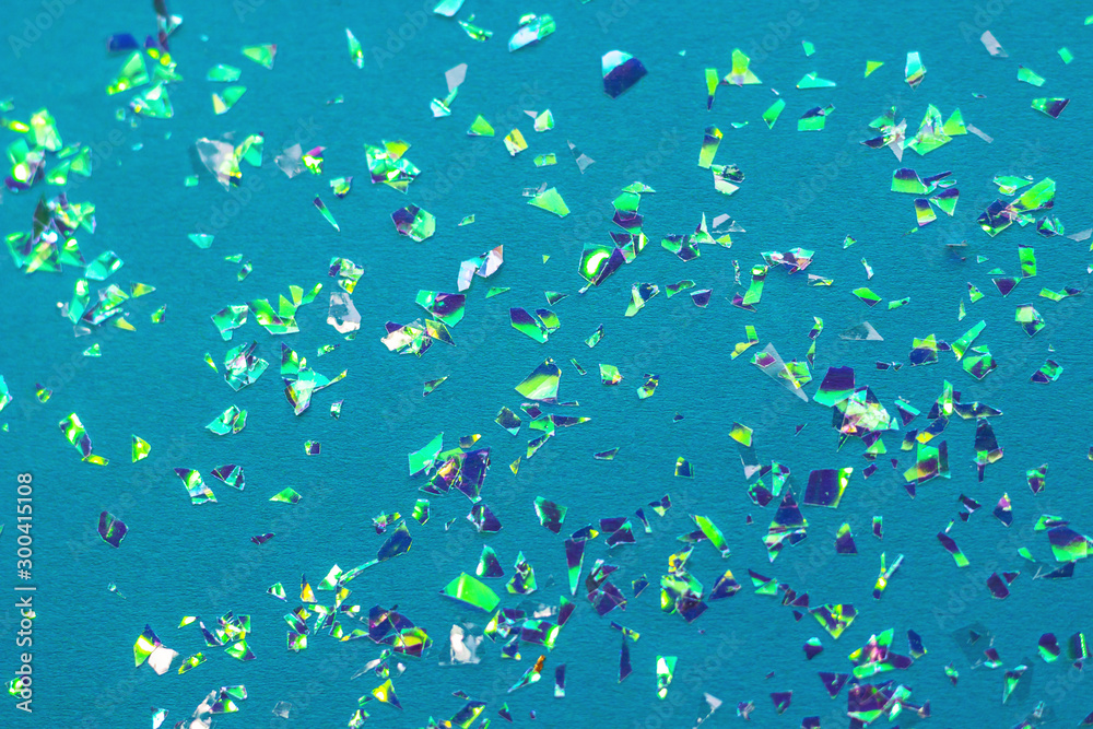 Multicolored holographic confetti on a blue background.