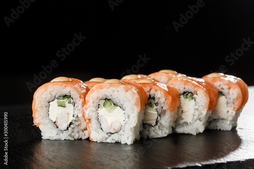 Sushi Rolls with cucumber, shrimp, salmon and Cream Cheese inside on black slate isolated. Philadelphia roll sushi with shrimp. Sushi menu. Horizontal photo.