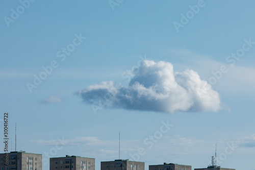 A large cloud is hanging above some buildings
