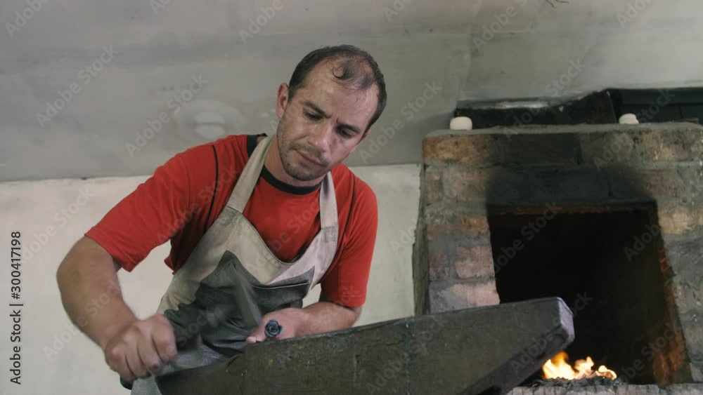 Inspired blacksmith is hitting a metallic rose with a hammer in a vintage workshop Inspired blacksmith is hitting a metallic rose with a hammer in a vintage workshop