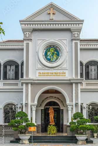 Wallpaper Mural Da Nang, Vietnam - March 10, 2019: Entrance part of Gray house of the Catholic Bishop of the local diocese under blue sky and green foliage. Statue of Jesus the sheppard with lamb.  Torontodigital.ca