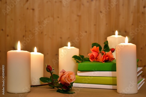 Romantic background with candles, books and flowers on a wooden. Picture for the beauty and health industry.