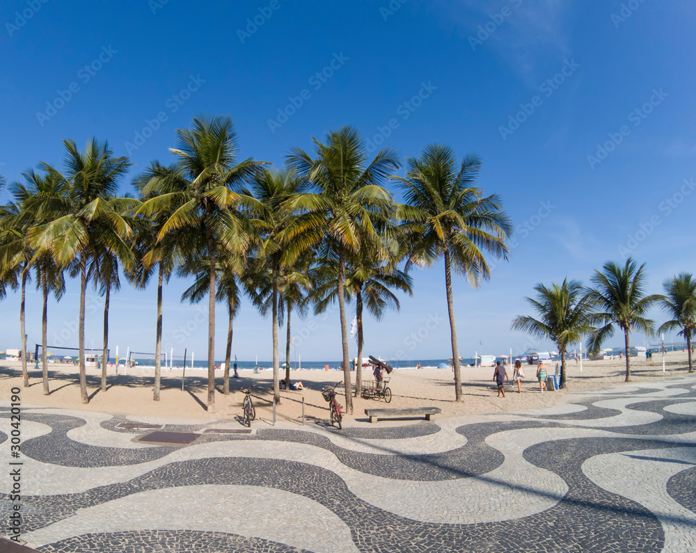 Copacabana Beach - View of famous geometric promenade and coconut trees with blue sky in the background