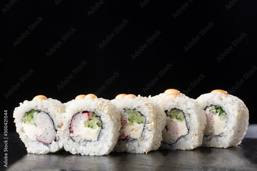 Sushi Rolls with shrimp , cucumber and cream cheese inside on black slate isolated. California rolls covered white sesame seeds. Sushi menu. Horizontal photo. Sushi Rolls with shrimp , cucumber and cream cheese inside on black slate isolated. California rolls covered white sesame seeds. Sushi menu. Horizontal photo.
