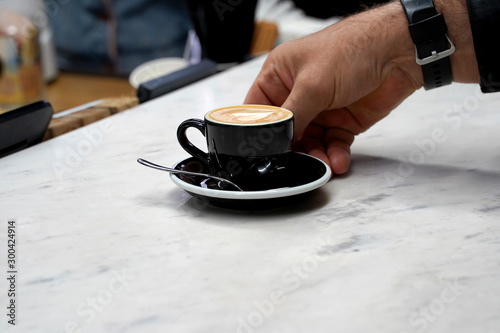  the client's hand takes his coffee from the table