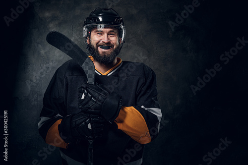Photo Happy toothless hockey player is posing for photographer with hockey stick