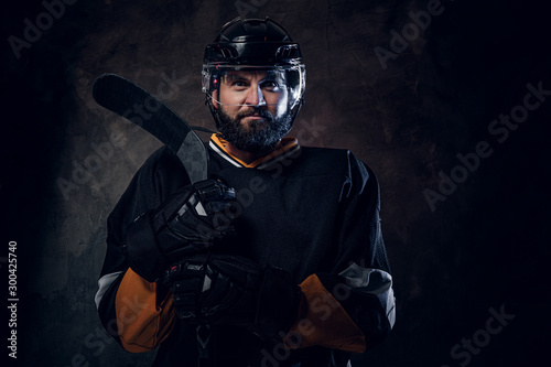 Serious pensive hockey player has a photo session at photo studio.
