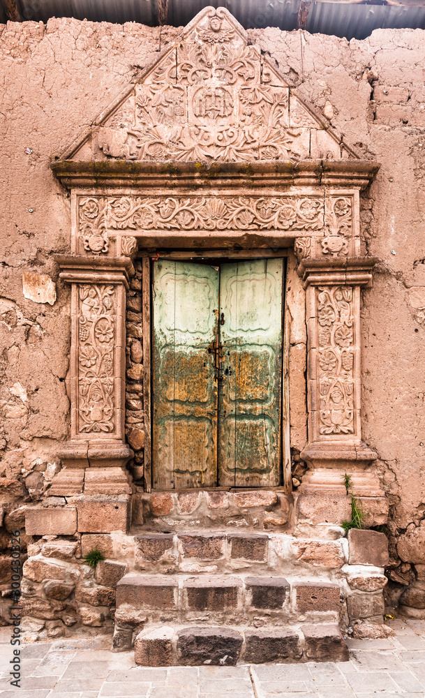 Entrance door of a clay house with decoration in relief on a street of Juli city, Puno region, Peru