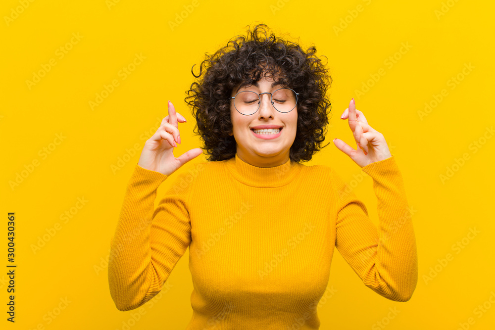 Φωτογραφία young pretty afro woman feeling nervous and hopeful, crossing fingers, praying a