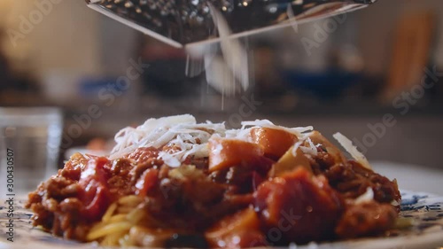 Close up of fresh Italian parmesan cheese being grated on top of hot steamy spaghetti with bolognese sauce photo