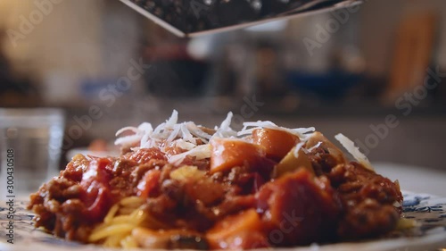 Close up of fresh Italian parmesan cheese being grated on top of hot steamy spaghetti with bolognese sauce photo