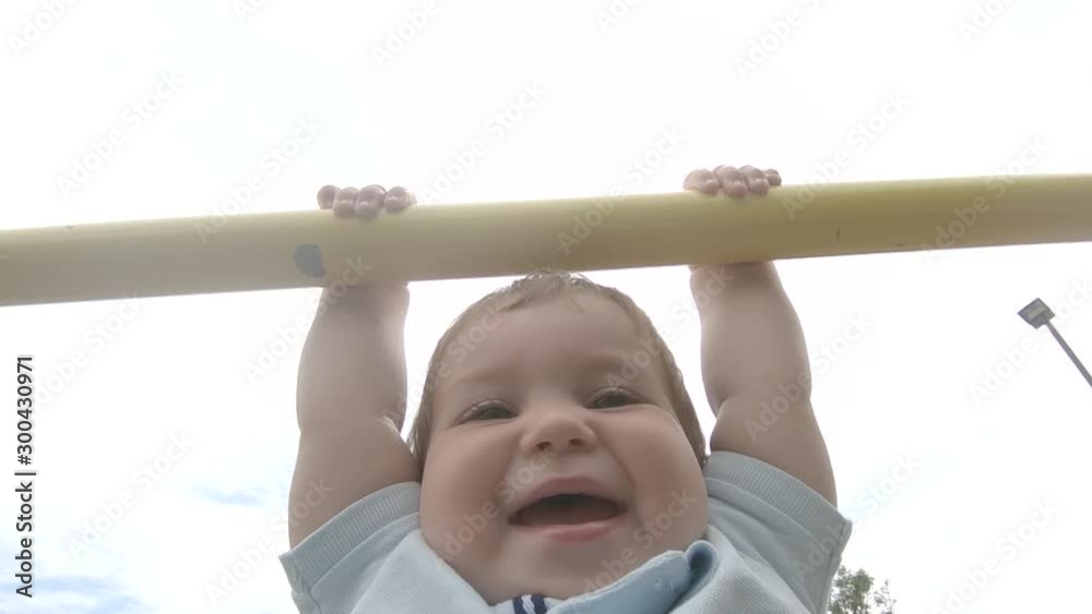 Slow motion close up little Caucasian boy lifting himself outside on pull up bar Slow motion close up little Caucasian boy lifting himself outside on pull up bar