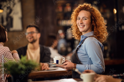 Young happy waitress serving coffee in a coffee shop. photo