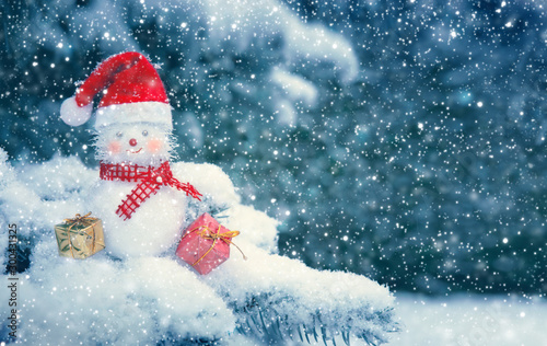 Christmas background with snowman with red scarf and santa claus hat .