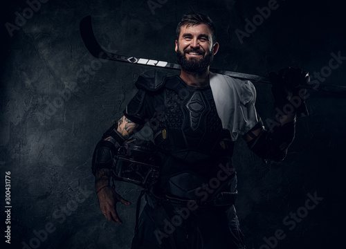 Fototapeta Naklejka Na Ścianę i Meble -  Confident emotional hockey player with hockey stick is posing for photographer.