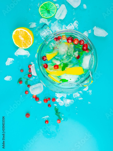 Fototapeta Naklejka Na Ścianę i Meble -  Refreshing lemon water in glass jug with ice cubes on blue background