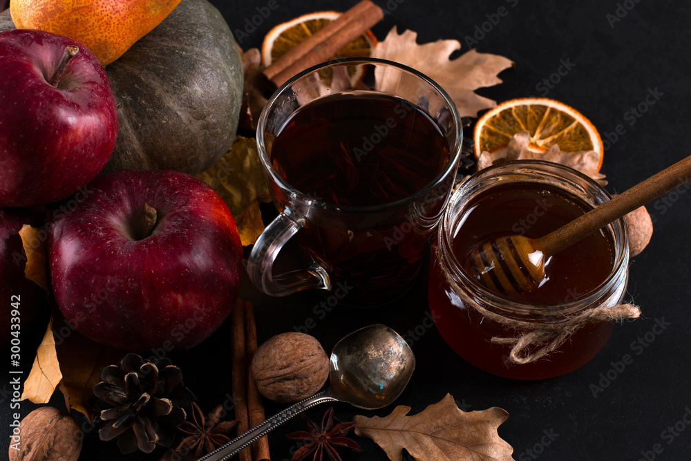 Tea, may liquid honey, fruits, cinnamon, dried oranges and nuts on a black background. autumn harvest, copy space. Tea, may liquid honey, fruits, cinnamon, dried oranges and nuts on a black background. autumn harvest, copy space.