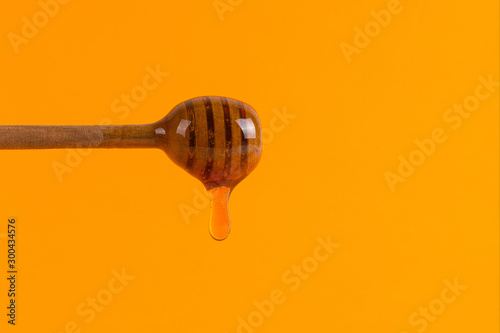 A stick for honey and a small jar, concept on a yellow background.