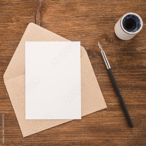 Envelope, ink pen, inkwell on wood table