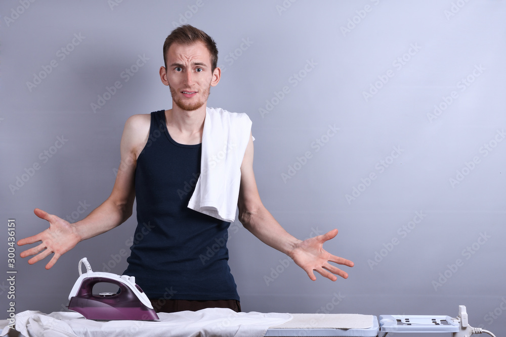 Young Happy Man Ironing Clothes On Ironing Board.husband doing clothing ironing at home Young Happy Man Ironing Clothes On Ironing Board.husband doing clothing ironing at home