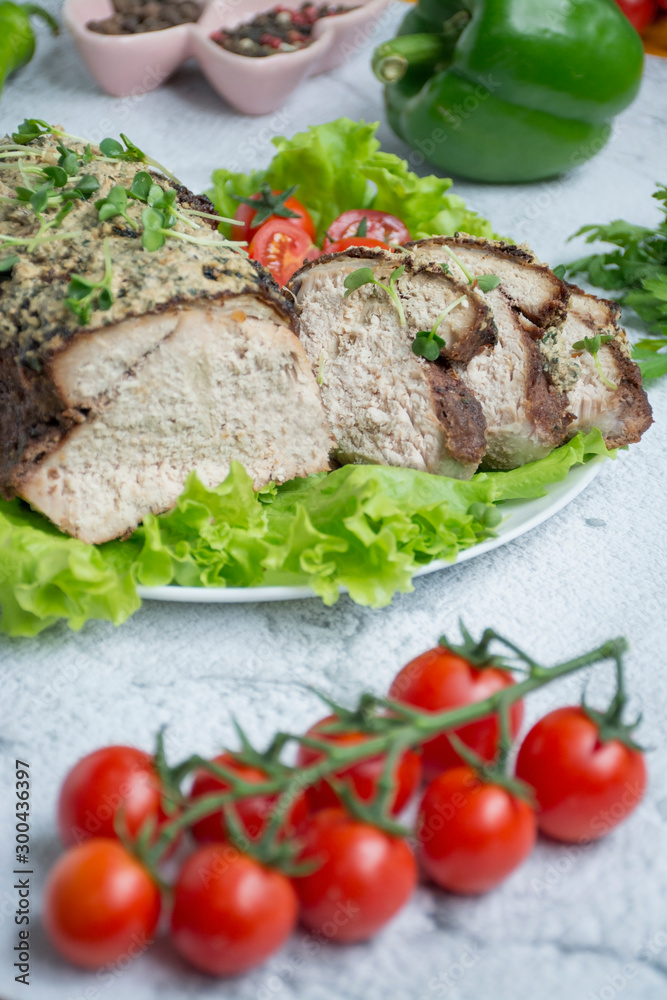 Baked pork chopped in a sauce of walnuts and mint on a white plate with fresh herbs and vegetables. Light background. Baked pork chopped in a sauce of walnuts and mint on a white plate with fresh herbs and vegetables. Light background.
