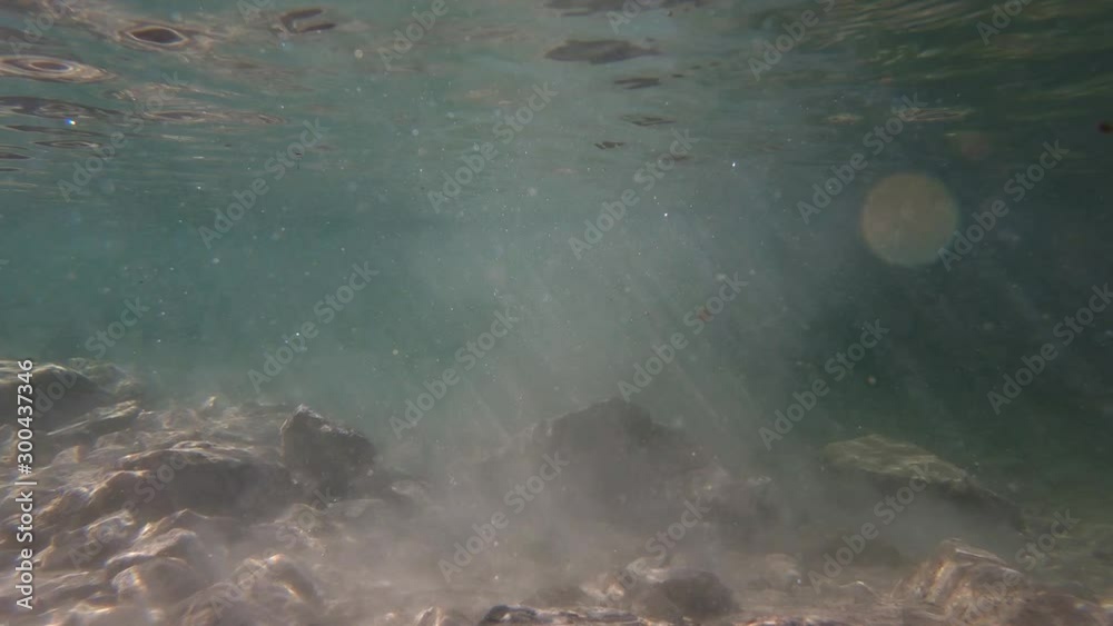 Slow motion underwater sun rays hitting rocky lake floor. Slow motion underwater sun rays hitting rocky lake floor.