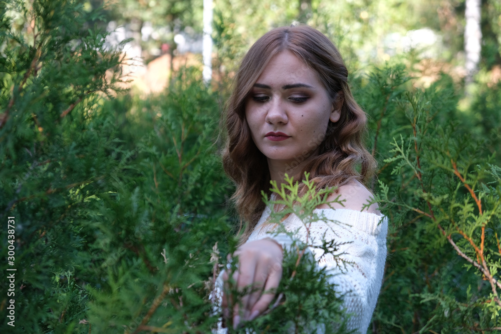 Naklejka premium sad young girl at green bushes background