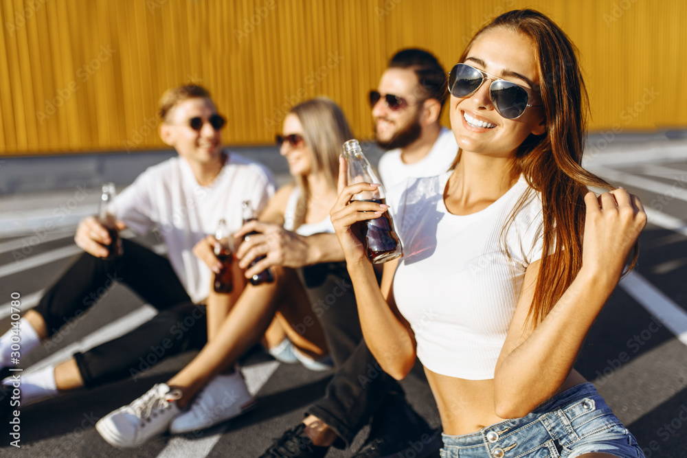 Fototapeta premium A group of young friends having fun and hanging out sitting in the city on the asphalt