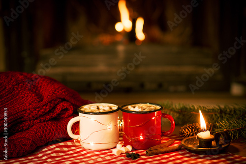 Christmas and New Year's mugs with cocoa by the fireplace with a warm sweater and cinnamon and anise