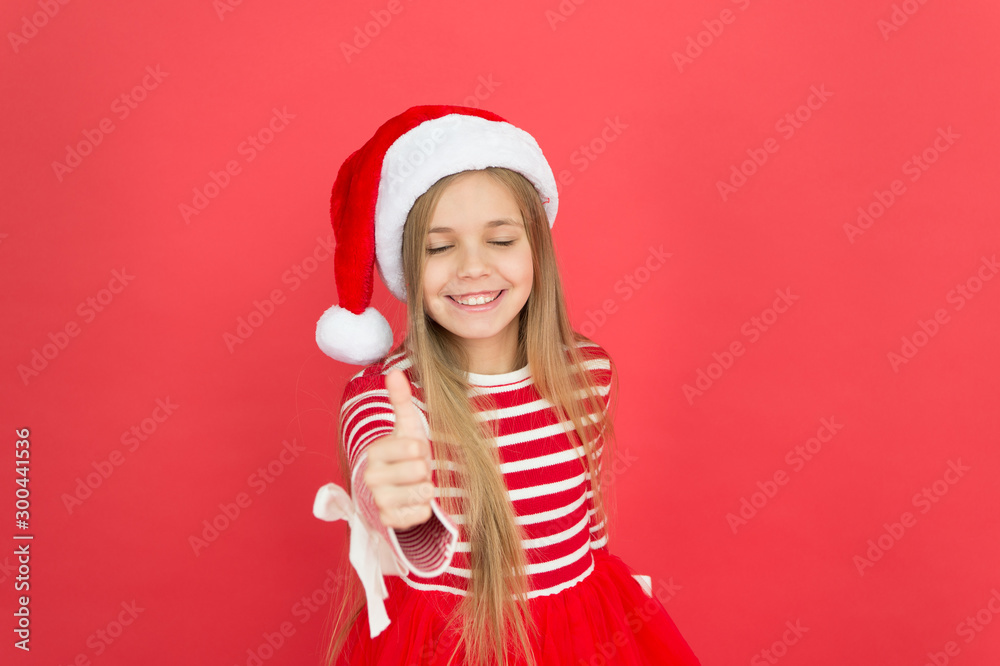 Thumbs up for new year. Happy girl smile with new year santa look. Little child show thumbs up gesture red background. New year party. Happy new year. Merry Christmas