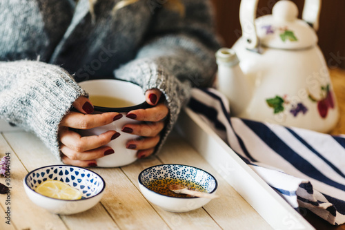 A female model is drinking herbal tea for flu, she is pouring herbal tea into a white enamel cup