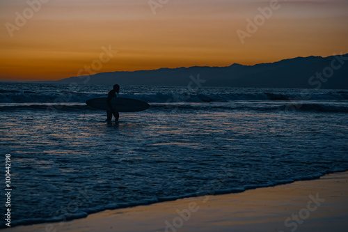 Sunset on the Pacific Coast in California  surfer and joggers run a sport