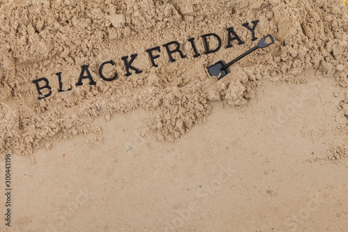 The concept of the inscription Black Friday placed in a sand hole dug with a shovel.
