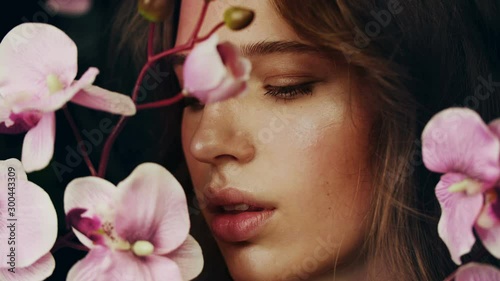 Face of beautiful girl among flowers of the archidea. Natural cosmetics and skin care. Exotic flower. Perfume Advertising.